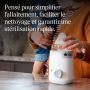 Maman tenant son bébé tout en sortant un biberon du chauffe-biberon Easiwarm
