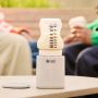 Upside down baby bottle placed on top of LetsGo bottle warmer on a table outside