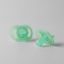 Two Night Glow soothers on a light grey background.