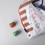 Sac à langer plié et deux sucettes Anytime sur fond gris clair.