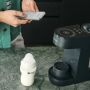Image de la machine Perfect Prep et du biberon Natural Start sur un comptoir de cuisine avec un parent en arrière-plan utilisant l&apos;application Tommee Tippee sur son téléphone