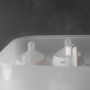 Open SteriDryer with steam coming out of it and showing bottle lids inside against a grey background