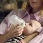 Close up image of a woman feeding a baby using a Natural Start bottle
