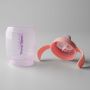 Pink Starter Spout cup base and lid laid out side by side against a grey background