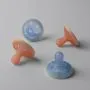 Four breast-like night glow soothers on a grey background.