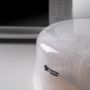 Close up of a microwave sterilizer on a kitchen worktop with a microwave in the background