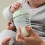 Close up image of a baby holding a Natural Start glass bottle