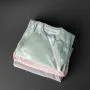 Three folded sleeping bags on a grey background