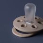 Close up of a Sculpted Clay soother silicone teat and shield with elliptical holes.