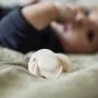 Close up of soother on bed next to baby