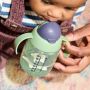 Close up of a child drinking from a green weighted straw cup
