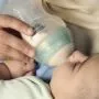 Close up image of a parent feeding a baby using an Advanced Anti-colic bottle
