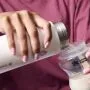 Gros plan d&apos;un parent versant du lait maternisé dans un biberon à partir d&apos;un flacon réfrigérant PrepGo