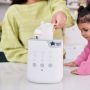 A woman using the easy-lift cradle to lower a baby bottle into a Multiwarm bottle warmer