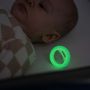 Baby sleeping with glowing in the dark pacifier next to them