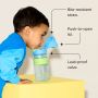 Toddler leaning on a yellow box and drinking from an on-the-go straw cup with pointers to the key product features