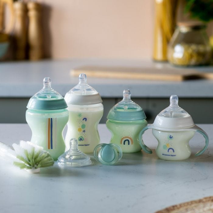 Newborn baby bottle starter kit with 4 bottles, teat, soother and bottle brush on kitchen bench.