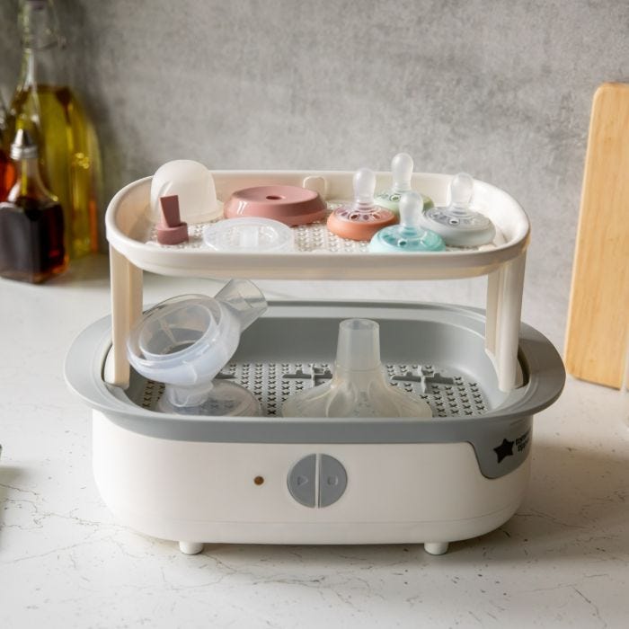 Open white steam steriliser on a kitchen counter with breastfeeding accessories inside