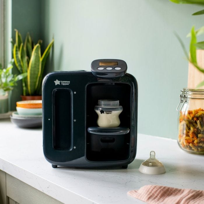 Un préparateur de biberons Prep Perfect Day & Night noir sur un comptoir de cuisine avec un biberon sur le support