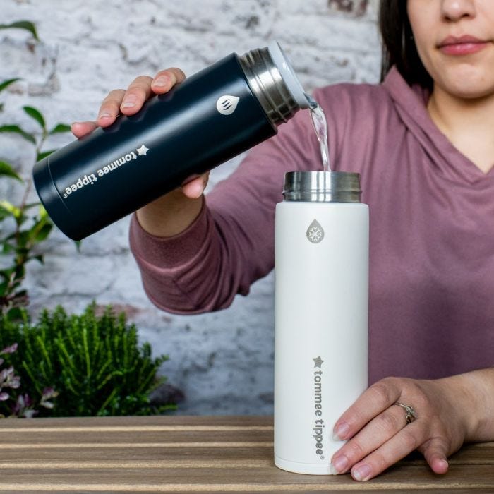 Femme assise dehors versant de l&apos;eau bouillante du thermos à eau chaude dans le thermos refroidisseur