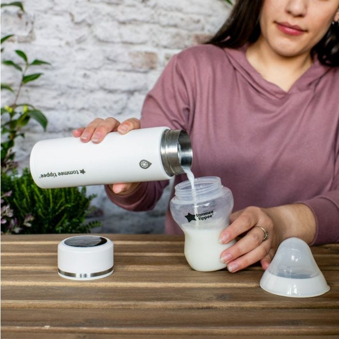 Woman pouring a freshly made formula feed into a sterile baby bottle