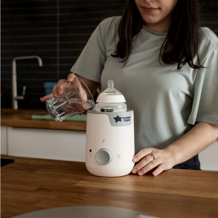 Femme debout dans la cuisine, versant de l&apos;eau dans son chauffe-biberon Easiwarm