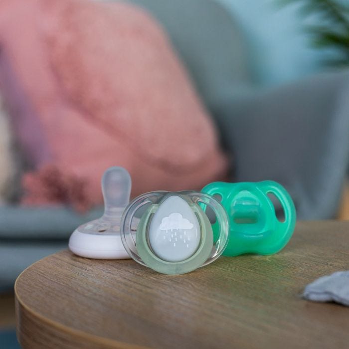 1x Breast-like, 1x Ultra-light and 1x Nighttime pacifier on a wooden table