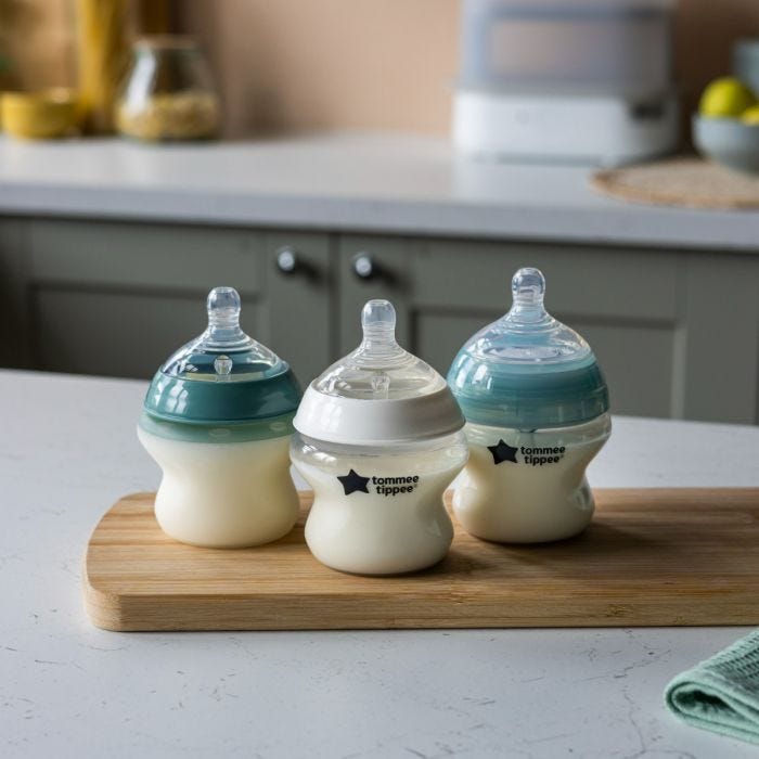 1x silicone, 1x Closer to Nature and 1x Advanced Anti-Colic 5oz baby bottle on wooden board in kitchen.