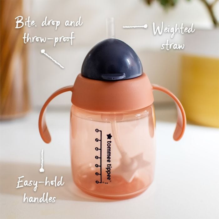 Pink weighted straw cup on a kitchen counter with pointers to its key features