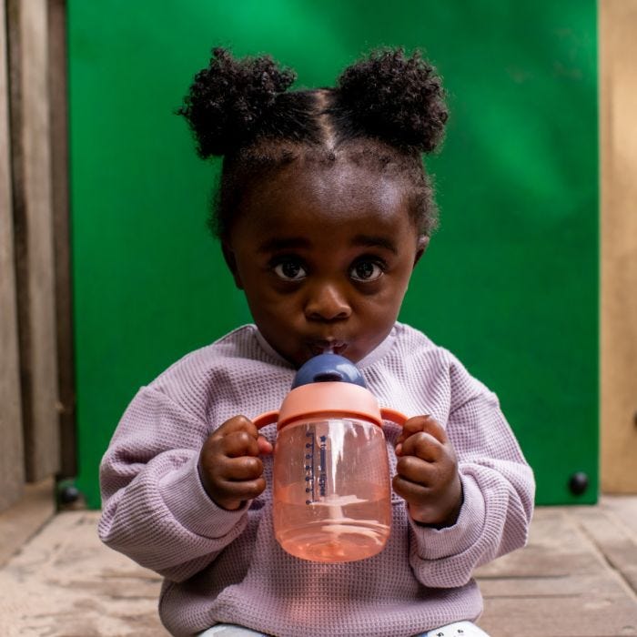 Little girl drinking from a pink weighted straw cup