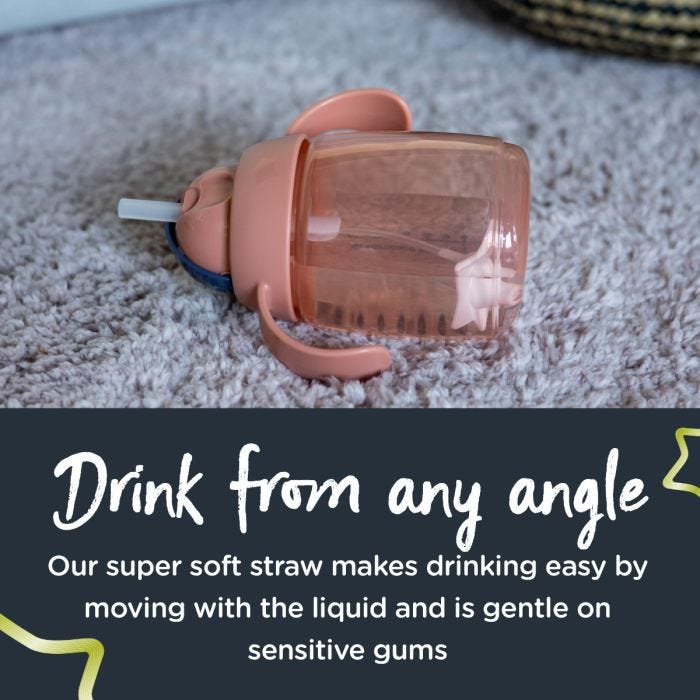 Pink weighted straw cup lying flat on a carpet with text about drinking from any angle