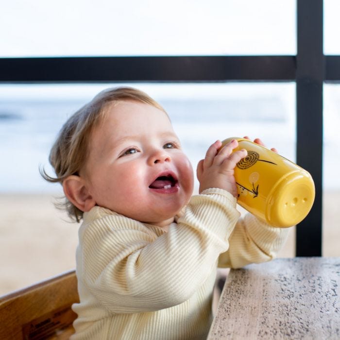 Toddler holding yellow sipper cup