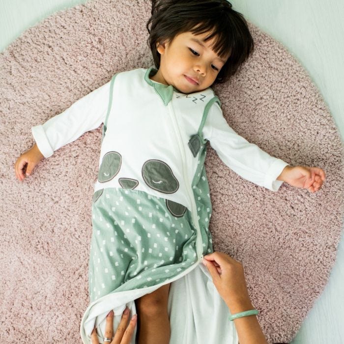 child lying on the floor wearing sleepbag