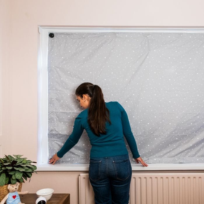 Woman fitting the blackout blind to a window.