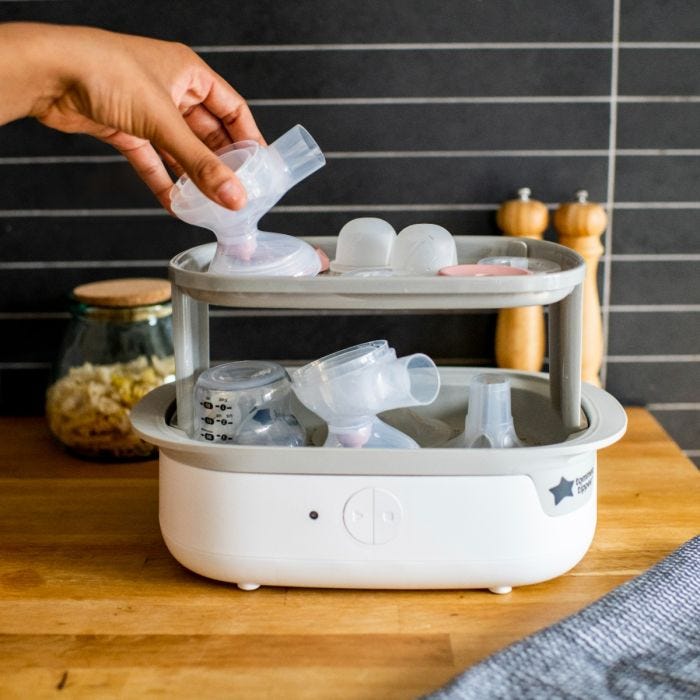 Woman placing separated parts of the electric pump in an electric steam sterilizer