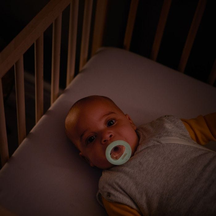 Baby lying in cot with Breast-like Night Time Soother in mouth