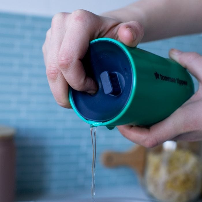Someone pressing the valve of a teal 360 cup to show how the water is released