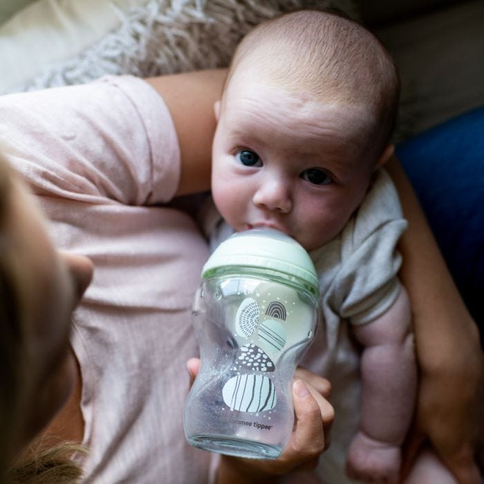 Mum feeding baby from glass baby bottle