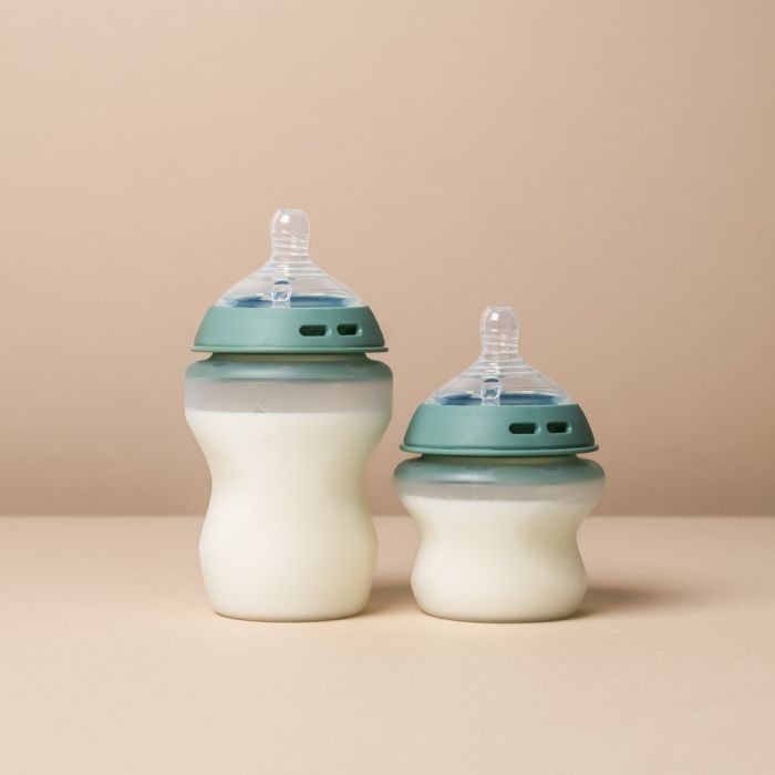 Two Natural Start Silicone baby bottles against a beige background
