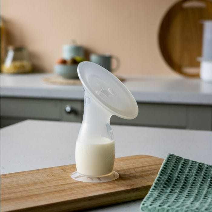 Silicone breast pump filled with breast milk on a kitchen counter