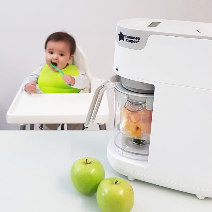 quick-cook-baby-food-maker-white-in-foreground-with-baby-in-highchair-in-background