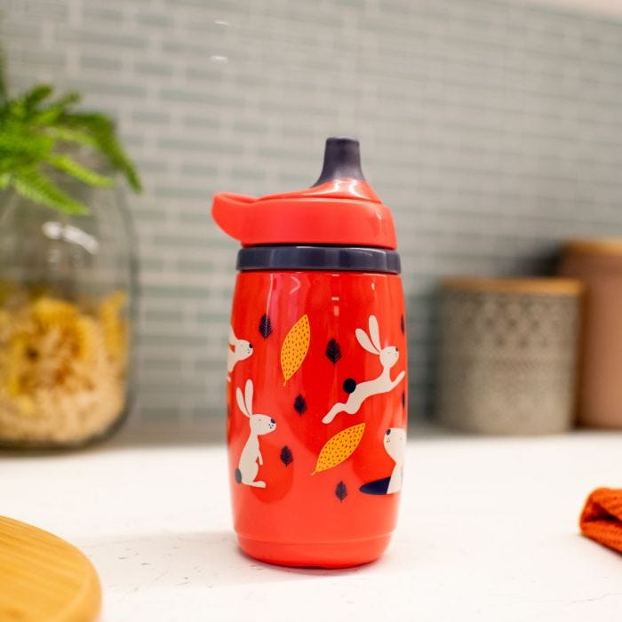 Tasse sportee verte posée à plat sur un canapé