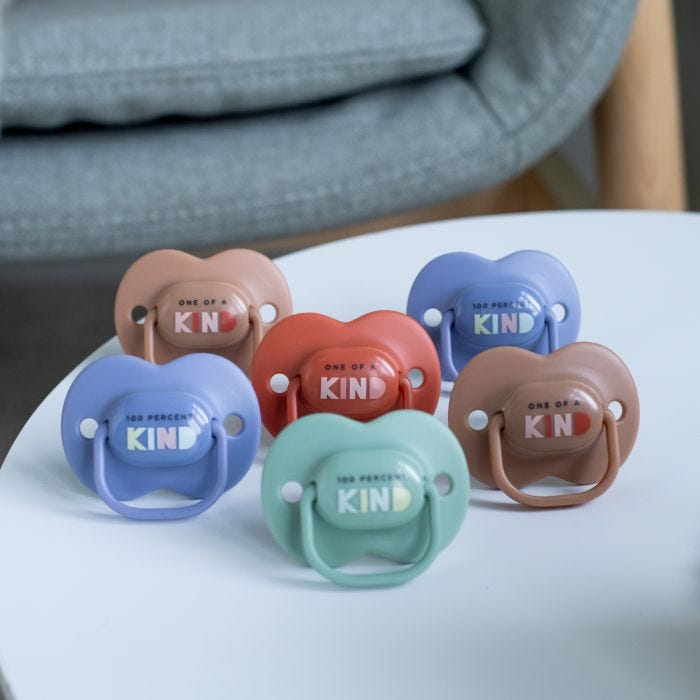 Anytime soothers in various colours lying on a white table.