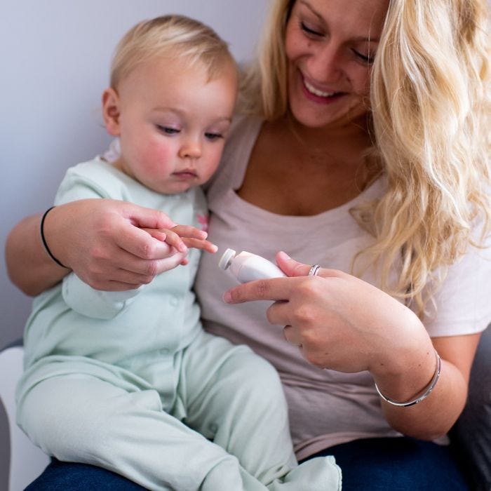 Maman limant les ongles de son bébé assis sur ses genoux