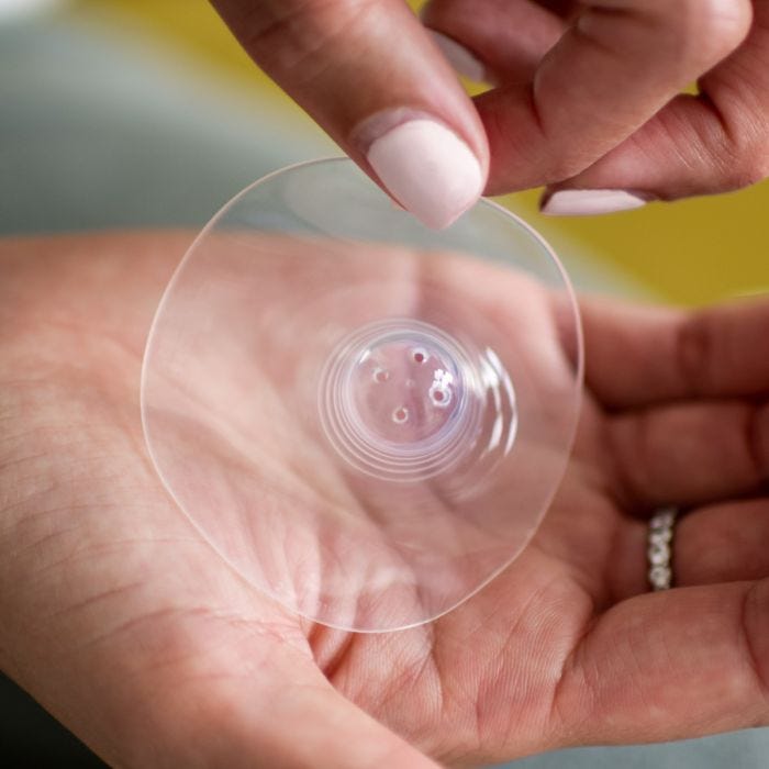 Woman holding a nipple shield with a view of the teat holes