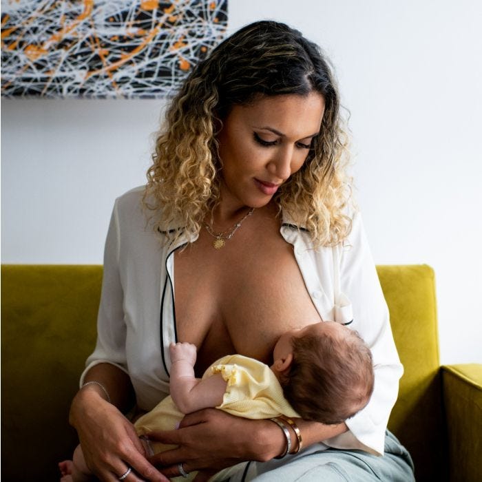 Woman sitting on a couch while breastfeeding her baby