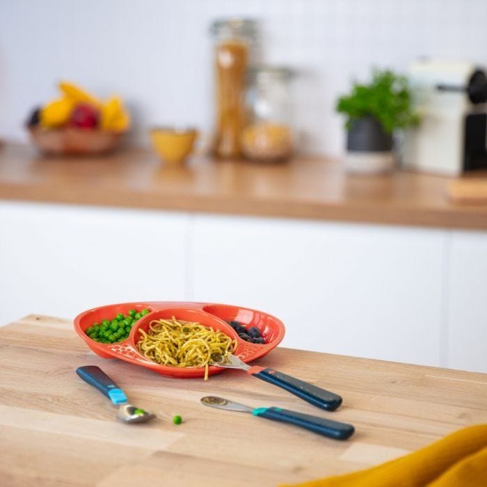 Big kids first cutlery set on table with plate full of food