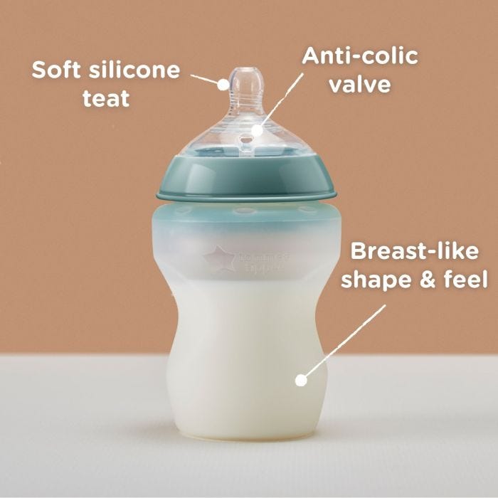 Silicone baby bottle on a table with pointers to its silicone teat, anti-colic valve and breast-like shape