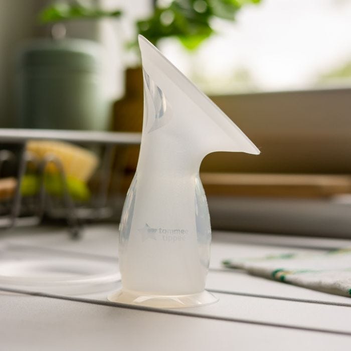 Silicone breast pump filled with breast milk on a kitchen counter