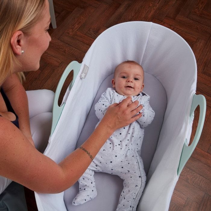 mum playing with baby lying in sleepee moses basket
